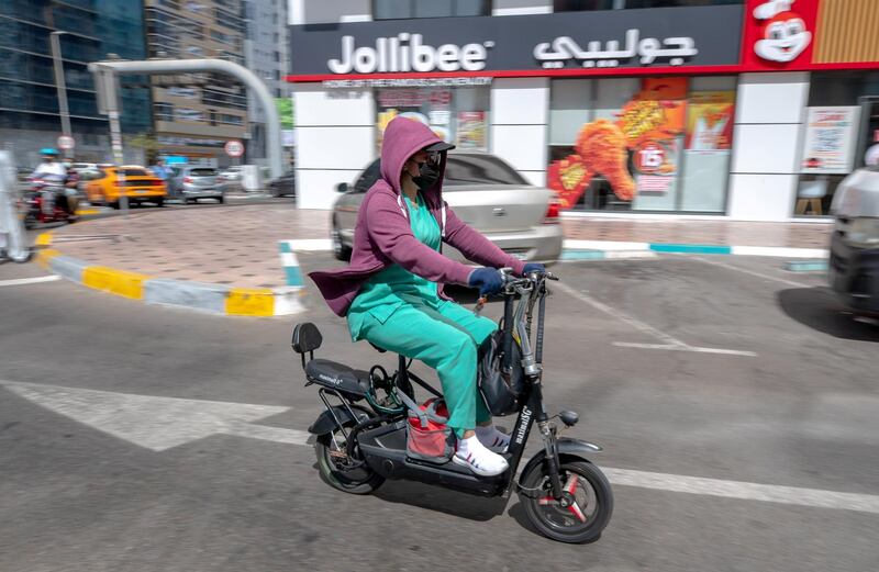 Abu Dhabi, United Arab Emirates, March 31, 2021.  A healthcare worker on an e-bike goes against traffic flow on Hamdan Street central Abu Dhabi.
Victor Besa/The National
Section:  NA
FOR:  Stock Images