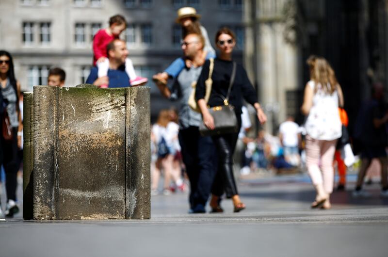 People walk past concrete barriers placed by police in front of the world famous gothic cathedral in Cologne, Germany, August 23, 2017.     REUTERS/Wolfgang Rattay