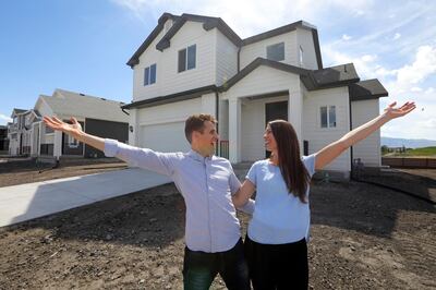 In this April 27, 2019, photo, Andy and Stacie Proctor stand in front of their new home in Vineyard, Utah. For some millennials looking to buy their first home, the hunt feels like a race against the clock. The Proctors ultimately made a successful offer on a three-bedroom house for $438,000 in Vineyard. (AP Photo/Rick Bowmer)
