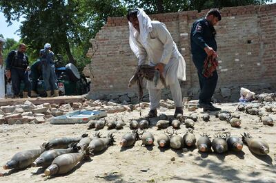 Afghan security officials inspect seized weapons near a damaged residential house from where a group of Islamic State (IS) gunmen were firing mortar shells while another group was raiding a prison, in Jalalabad on August 4, 2020. - At least 29 people were killed when gunmen attacked a jail in the eastern city of Jalalabad on August 3, shattering the relative calm of the final day of a three-day ceasefire between the Taliban and Afghan forces. (Photo by NOORULLAH SHIRZADA / AFP)