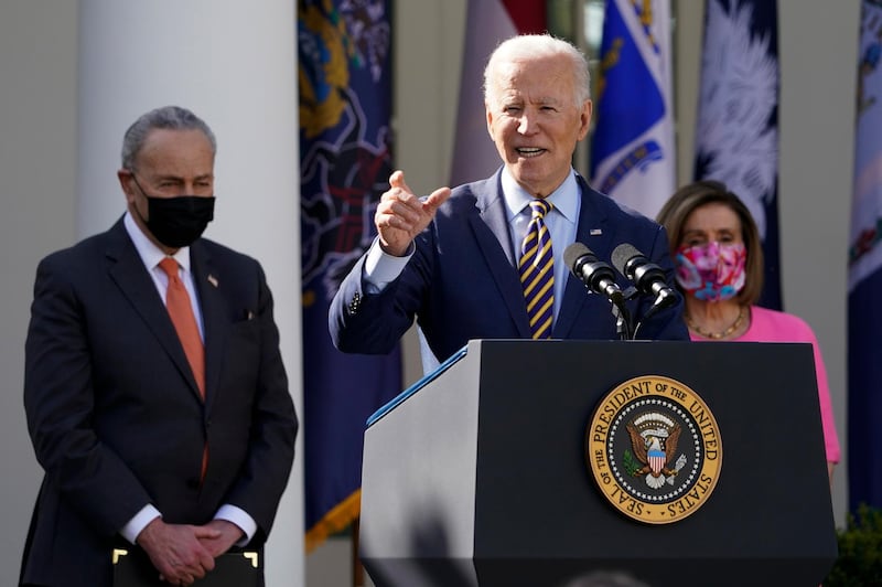 President Joe Biden speaks about the American Rescue Plan, a coronavirus relief package, in the Rose Garden of the White House, Friday, March 12, 2021, in Washington. Senate Majority Leader Chuck Schumer of N.Y., left, and House Speaker Nancy Pelosi of Calif., listen. (AP Photo/Alex Brandon)