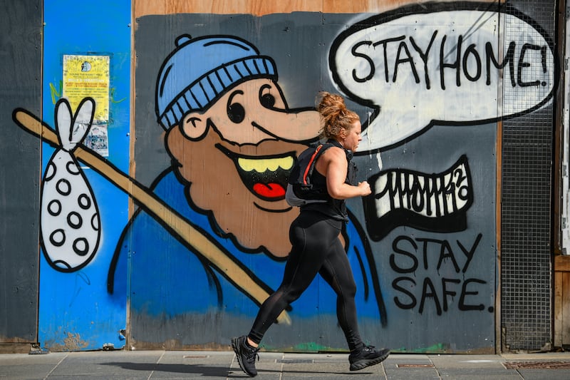 A member of the public makes their way past some graffiti on Sauchiehall Street in Glasgow, which encourages people to 'stay home'. Getty Images