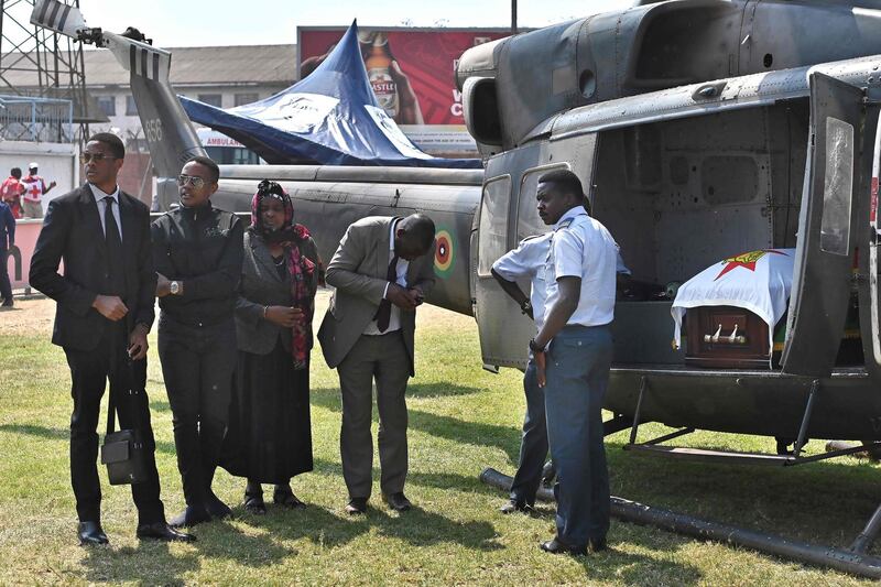 The sons of Zimbabwe's former President, the late Robert Mugabe, Robert Junior (L), Chatunga (2R) and her sister Regina Gata stand near the helicopter carrying the casket of Mugabe at Rufaro stadium where his body lays in state for a second day. Mugabe died in Singapore last week aged 95, leaving Zimbabweans divided over the legacy of a leader once lauded as a colonial-era liberation hero, but whose autocratic 37-year rule ended in a coup in 2017.  AFP