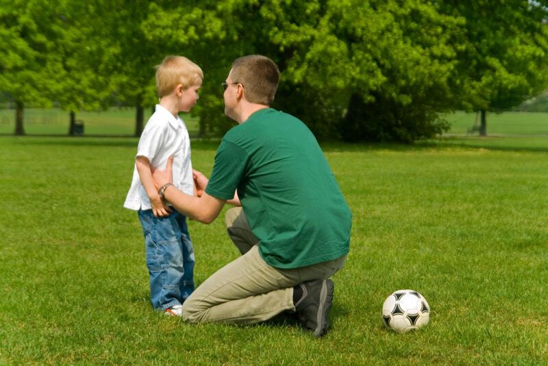 A8ME2X Horizontal portrait of a young father disciplining his young son during a game of football in the park. Image shot 2007. Exact date unknown.