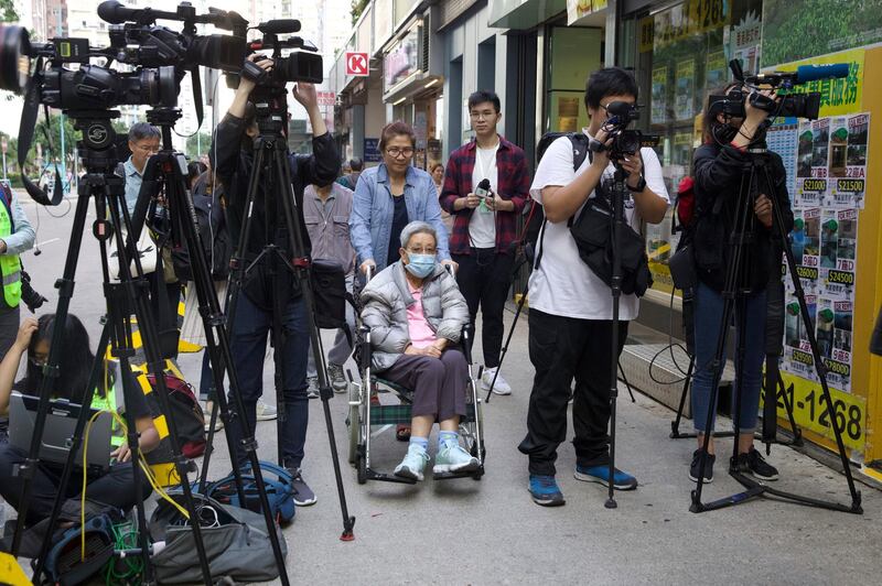 A woman is wheeled past journalists outside a polling centre in Hong Kong. AP Photo