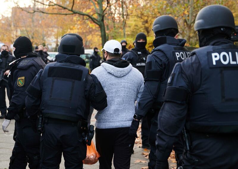 Police officers escort a person for an identity check in Berlin. AP Photo