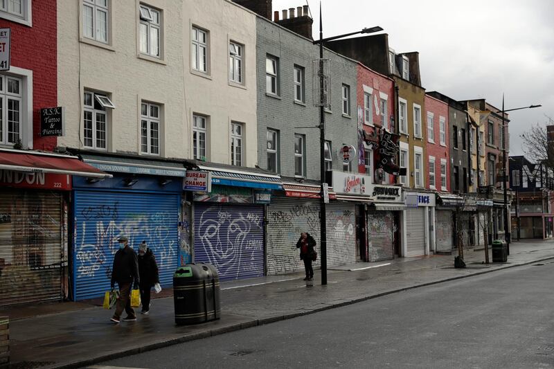 People walk past temporarily closed shops in Camden Town, an area of London usually bustling with tourists and visitors to its market. AP Photo