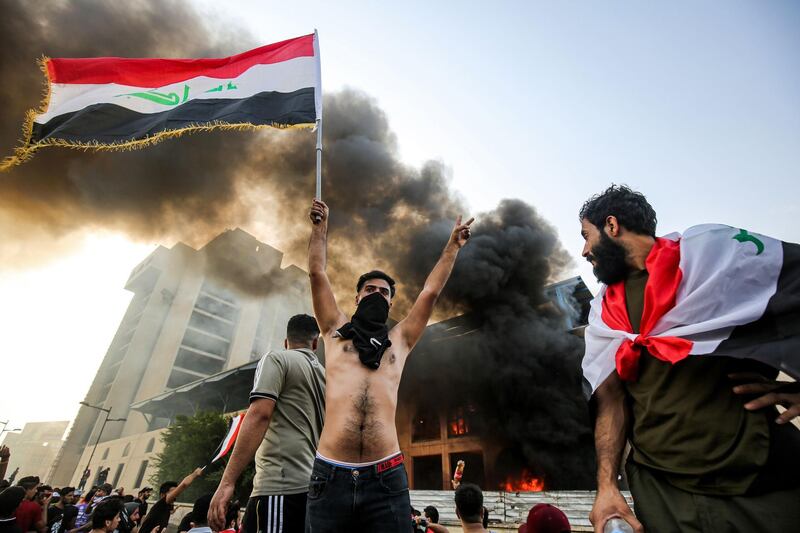 A masked protester flashes the victory sign in Baghdad's Tahrir Square. AFP