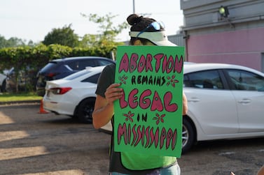 A clinic escort holds a sign reminding women that "abortion remains legal in Mississippi." The National / Willy Lowry