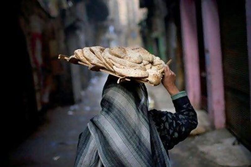 An Egyptian woman walks trough an alley in the al-Azhar quarter carrying a tray of fresh bread, in Cairo, Egypt. AP Photo/Bernat Armangue