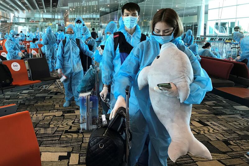 A Vietnamese woman carries a stuffed animal while boarding a repatriation flight from Singapore to Vietnam, at Changi airport, Singapore. Reuters