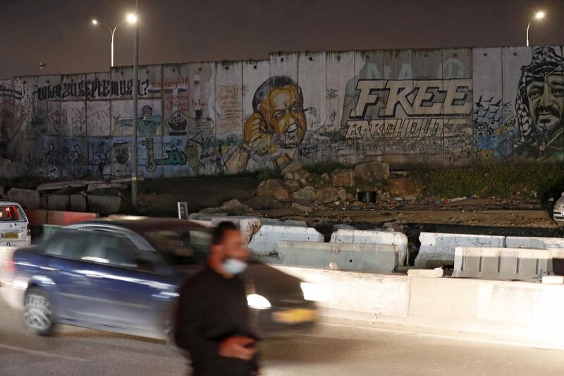 A picture taken on March 31, 2021 near the Israeli Qalandiya checkpoint, between Jerusalem and Ramallah, shows a mural of Fatah leader Marwan Barghouti and late Palestinian leader Yasser Arafat on a section of Israel's separation wall. AFP