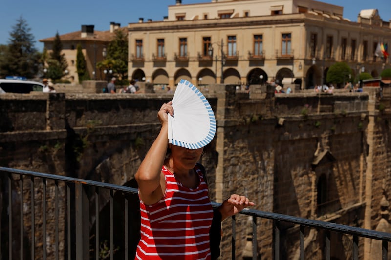 A woman uses a fan as a sunshade as spring temperatures rival those of summer in Ronda, southern Spain. Reuters