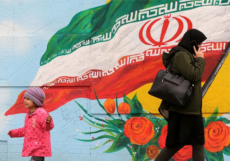 A woman walks past a mural with the Iranian national flag in Tehran, on February 20, 2020 on the eve of parliamentary election.
  / AFP / ATTA KENARE
