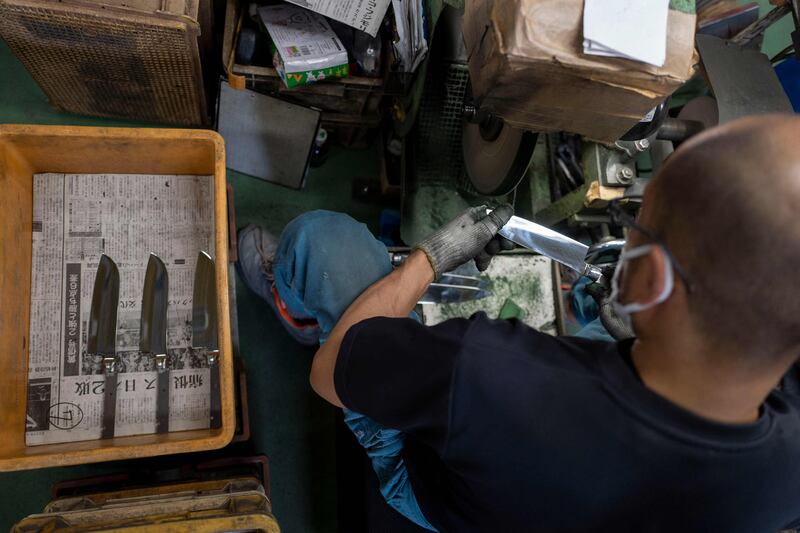 A worker checks the quality of a knife being polished