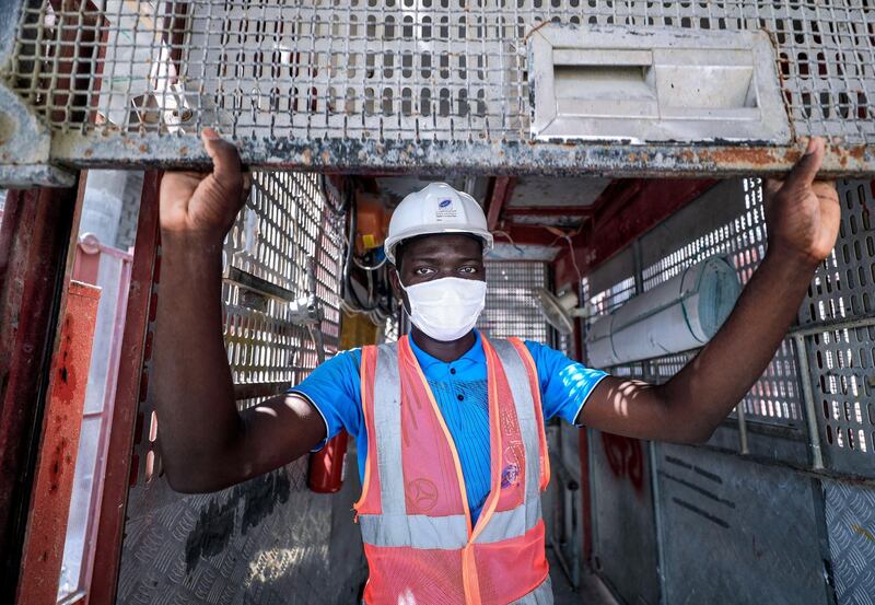 Abu Dhabi, United Arab Emirates, September 27, 2020.  An elevator technician rolls down the metal safety doors of the lift at the Al Raha Gardens construction site, Abu Dhabi.
Victor Besa/The National
Section:  NA
Reporter:  Haneen Dajani