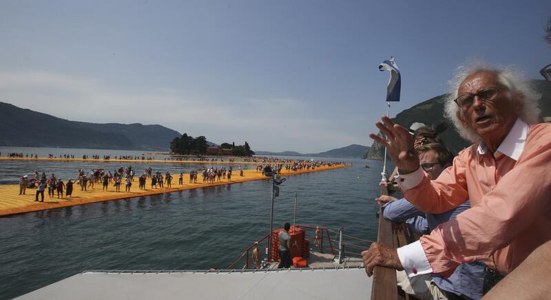 Artist Christo, waves from a boat sailing around his installation entitled The Floating Piers. Luca Bruno / AP photo