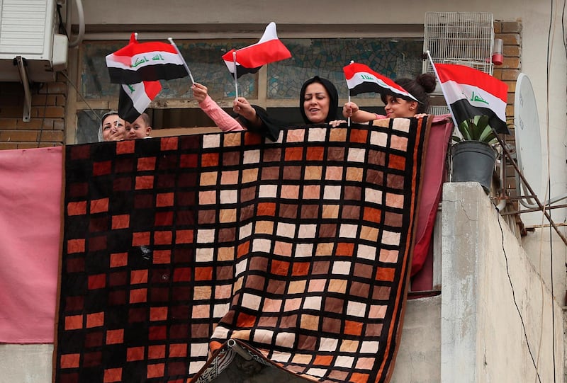 People wave national flags in solidarity with the families of those who have died or are ill with the coronavirus and support for doctors and nurses fighting to save them, in central Baghdad, Iraq. AP Photo