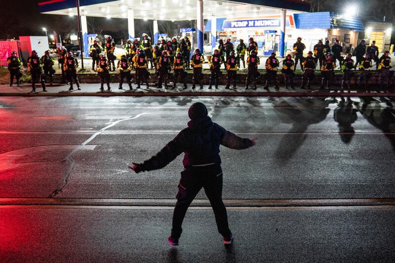 A demonstrator heckles security forces as they advance towards a petrol station in Minnesota, US. Crowds protesting against the police shooting of Daunte Wright were ordered to disperse on Monday night. AP