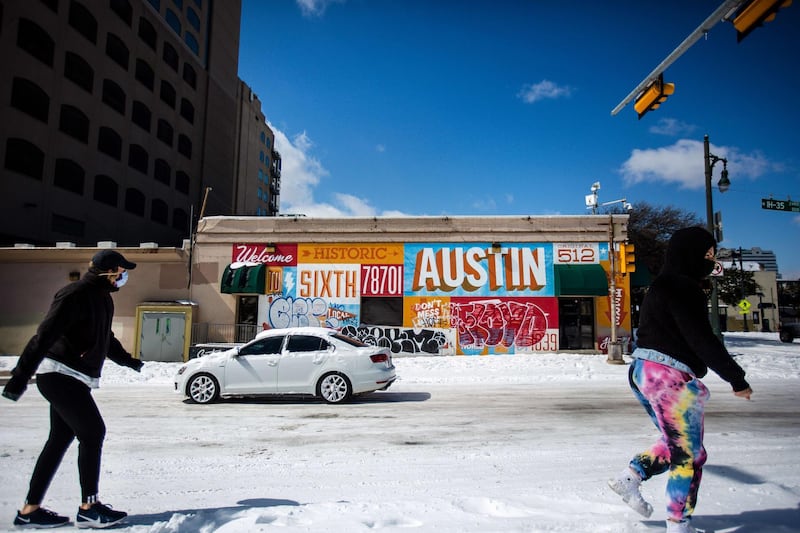 Pedestrians walk on along a snow-covered street in Austin. Winter storm Uri has brought unusual cold to Texas, causing traffic delays and power cuts. Storms have swept across 26 states. AFP