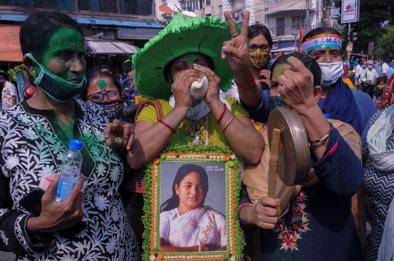 Supporters of Trinamool Congress party chief Mamata Banerjee holding an earlier photograph of her celebrate early lead for the party in the West Bengal state elections in Kolkata, India, Sunday, May 2, 2021. (AP Photo/Ashim Paul)