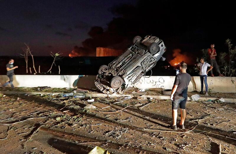 People gather by cars destroyed following an explosion at the port of Lebanon's capital Beirut. AFP