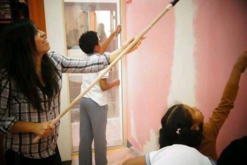 Volunteer Alex Sanchez, with her three children, having fun painting a classroom at the Future Centre for Special Needs in Abu Dhabi.