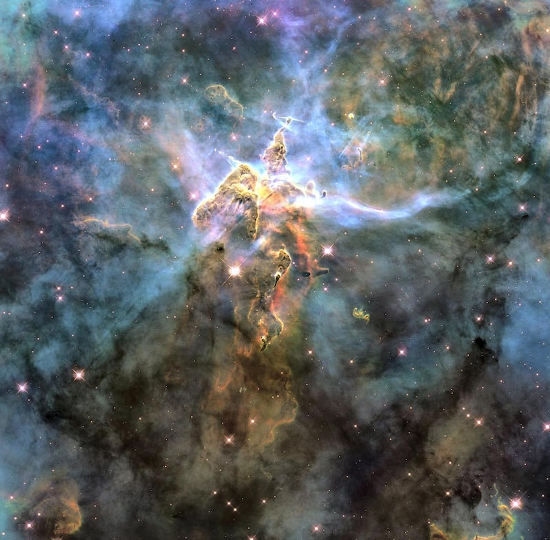 The NASA Hubble Space Telescope photograph, which is stranger than fiction, captures the chaotic activity atop a three-light-year-tall pillar of gas and dust that is being eaten away by the brilliant light from nearby bright stars. The pillar is also being assaulted from within, as infant stars buried inside it fire off jets of gas that can be seen streaming from towering peaks. This turbulent cosmic pinnacle lies within a tempestuous stellar nursery called the Carina Nebula, located 7,500 light-years away in the southern constellation Carina. NASA