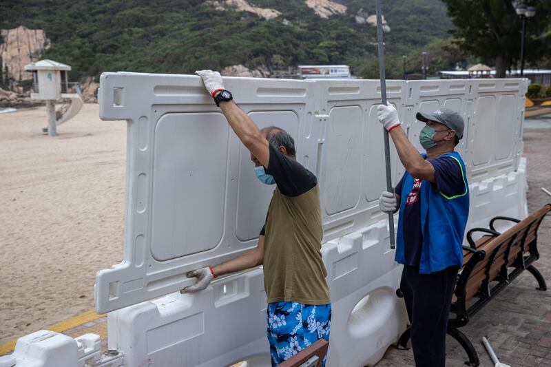 Staff erect fences to block access to Shek O beach in Hong Kong . Photo: EPA