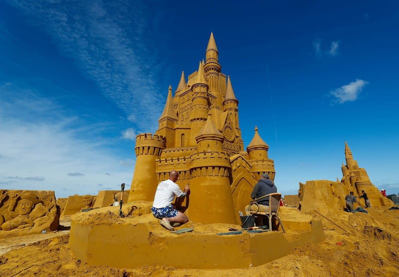 A sand carver works on a castle sculpture during the Sand Sculpture Festival. Yves Herman / Reuters