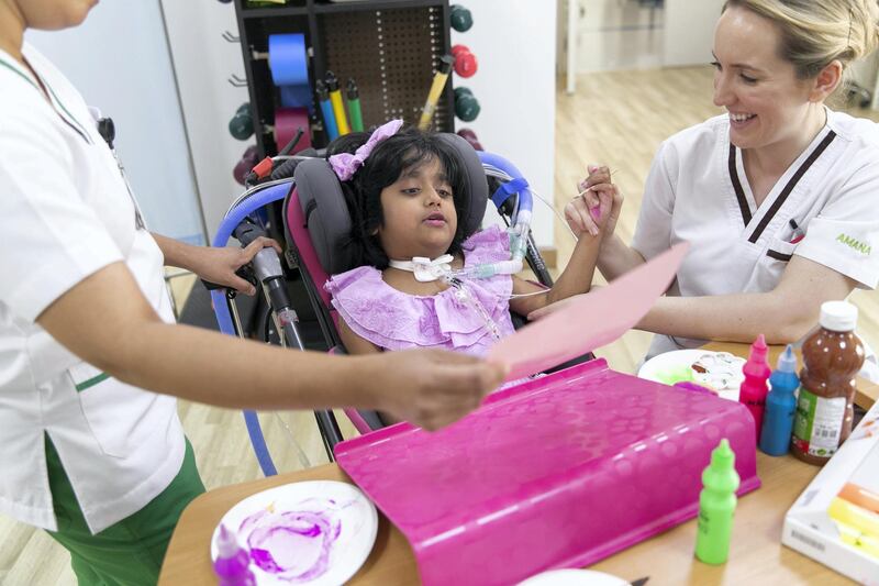 ABU DHABI, UNITED ARAB EMIRATES - JUNE 13, 2018. 

Meznah Basaloum painting a flower with Patricia Smith, a physiotherapist at Amana Healthcare.

An accident 2 years ago left little Meznah  paraplegic below the neck. Now 7 years old, Meznah has been strong and taking big steps after rehabilitation and physiotherapy sessions in Amana Heathcare.

(Photo by Reem Mohammed/The National)

Reporter: Nick Webster
Section: NA
