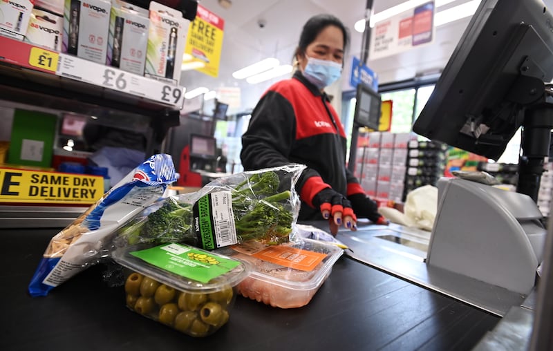 A cashier attends to customers at a supermarket till in London, Britain, 28 April 2022. EPA