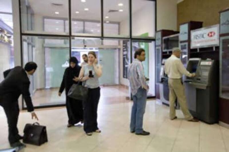 Customers queue at an HSBC ATM machine at Marina Mall.