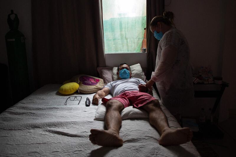 Nurse Marcicleia Gomes cares for her brother, nursing technician Marcio Moraes, 43, who is infected with Covid-19, at his home in Manaus, Brazil.  Moraes' daughters Laura and Lais had to ration oxygen to make a tank last longer as they transferred him to a hospital, crashing on the way. After he was discharged due to lack of space, another eight family members began to show symptoms, forcing his sister, nurse Marcicleia Gomes, 39, to quit her job in Brasilia to permanently assist them. According to Lais, “it has been an endless war for about 30 days”. AFP