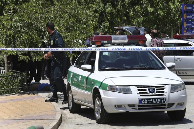 The body of a terrorist, at background left, lies on the ground while police control the scene at the shine of late Iranian revolutionary founder Ayatollah Ruhollah Khomeini. Ebrahim Noroozi / AP Photo