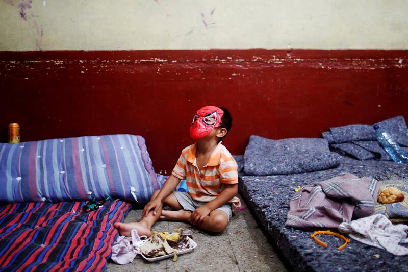 A child plays with a Spiderman mask as he eats dinner in a shelter in a local school after the Fuego volcano eruption damaged his community in Escuintla, Guatemala. Carlos Jasso / Reuters