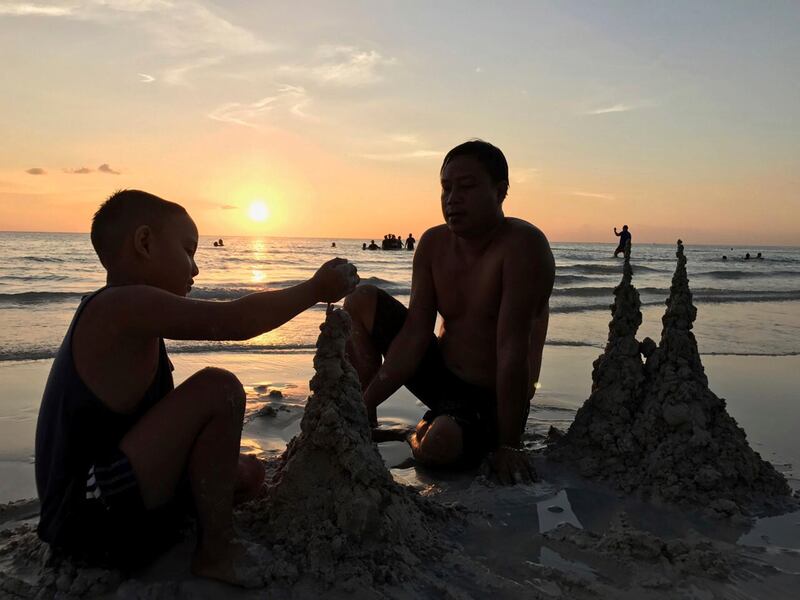 A father and son build sandcastles. AP Photo