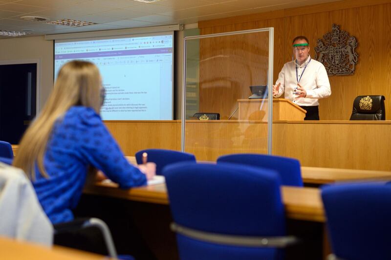 Lecturer Ian Bowden teaches law students from behind a perspex screen at the University of Bolton. Oli Scarff / AFP