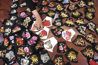 A worker points at colourful hand-embroidered face masks, used as a preventive measure against the spread of the COVID-19 novel coronavirus, at designer Do Quyen Hoa's workshop in Hanoi on April 13, 2020. (Photo by Nhac NGUYEN / AFP)
