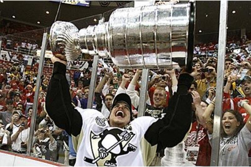 The Pittsburgh Penguins captain Sidney Crosby lifts the Stanley Cup in front of cheering fans.