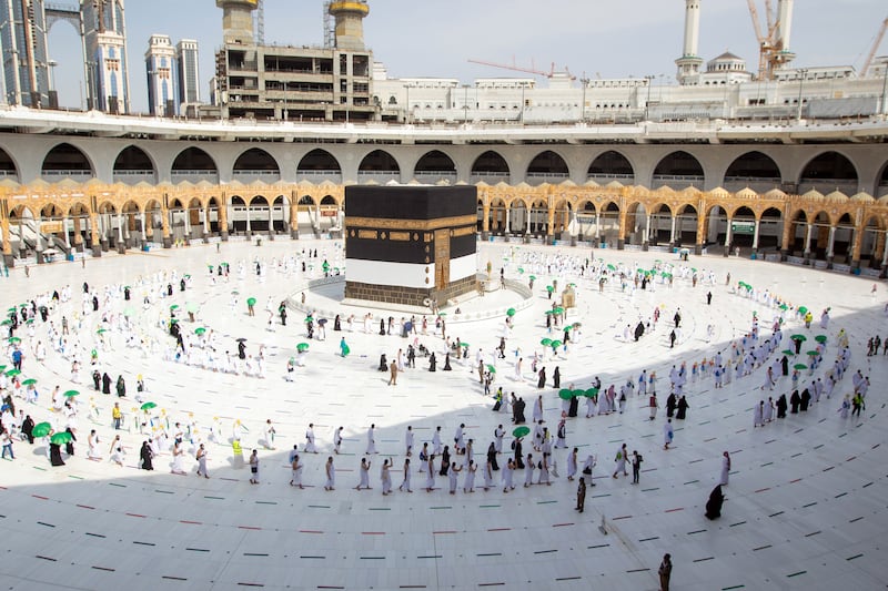 Muslim pilgrims, wearing protective face masks, circle the Kaaba.