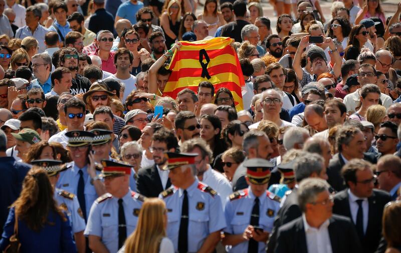 People holding a Catalan flag gather for a minute of silence in memory of the terrorist attacks victims in Las Ramblas, Barcelona, Spain, Friday, Aug. 18, 2017. Spanish police on Friday shot and killed five people carrying bomb belts who were connected to the Barcelona van attack that killed at least 13, as the manhunt intensified for the perpetrators of Europe's latest rampage claimed by the Islamic State group. (AP Photo/Francisco Seco)