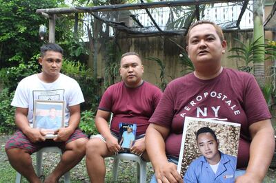 In this photo taken on June 29, 2020, brothers Rocky (L), Mike (C) and Lorenzo (R) pose for photos while holding a portrait of their brother Cherokee Capajo at home in Dingle, Iloilo province, central Philippines. From engineers on cargo ships to waiters on luxury cruise liners, ocean-based workers around the world have been caught up in what the United Nations warns is a growing humanitarian crisis that has been blamed for several suicides. - To go with AFP story Health-virus-Philippines-India-shipping-logistics, Cecil MORELLA with Aishwarya KUMAR in New Delhi 
 / AFP / - / To go with AFP story Health-virus-Philippines-India-shipping-logistics, Cecil MORELLA with Aishwarya KUMAR in New Delhi 
