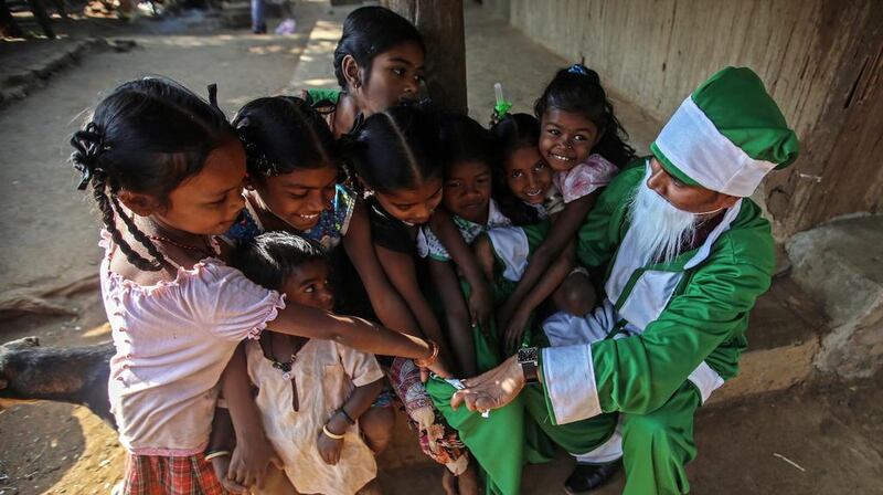 A man dressed as Santa Claus distributes sweets to children of tribal families, inside Sanjay Gandhi National Park, in Mumbai, India.  Divyakant Solanki / EPA