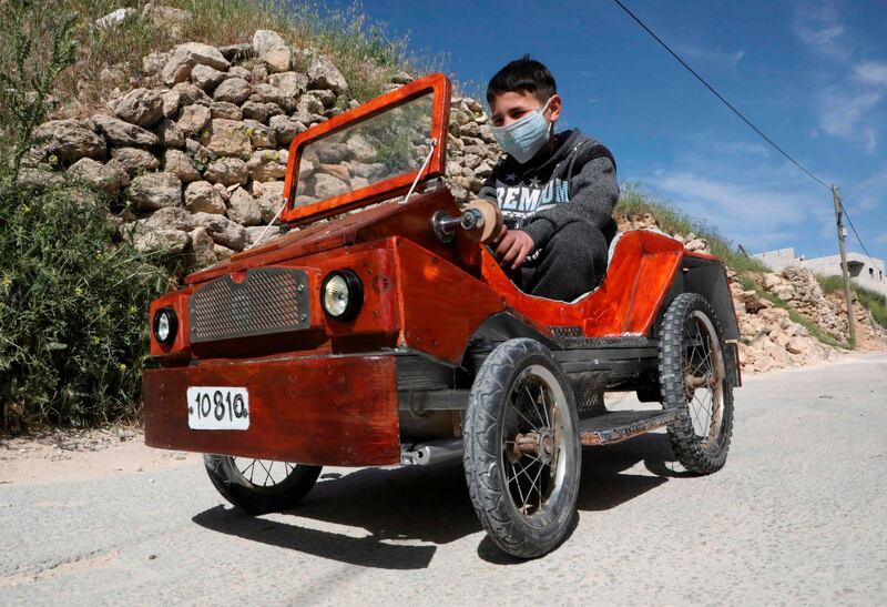 A Palestinian boy drives the handmade electric car named "corona" his father Fawzi Al Natsheh built in the West Bank town of Hebron.  AFP