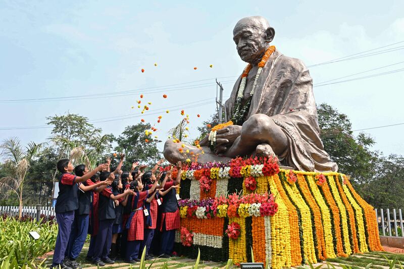 School students scatter flowers on the statue of Mahatma Gandhi on his death anniversary in Hyderabad on January 30, 2023.  - The death anniversary of Gandhi, who is widely known in India as Bapu (father), is also observed as Martyr's Day in the country.  (Photo by NOAH SEELAM  /  AFP)