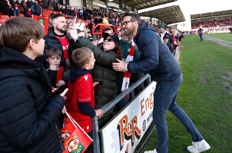 A fan takes a photo with Wrexham co-owner Ryan Reynolds before the match. Reuters