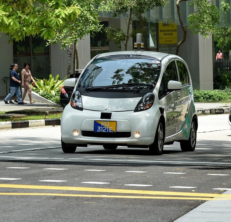 A driverless car (L) is seen on a trial test on the road in Singapore on August 29, 2016. - A US compnny which launched the world's first public trials of driverless cars in Singapore plans to expand the tests in three other Asian countries, a company executive said August 29. (Photo by ROSLAN RAHMAN / AFP)