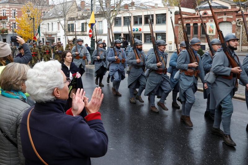 A local resident applauds as history enthusiasts dressed as French soldiers parade during a commemoration ceremony in Epernay, France. Reuters