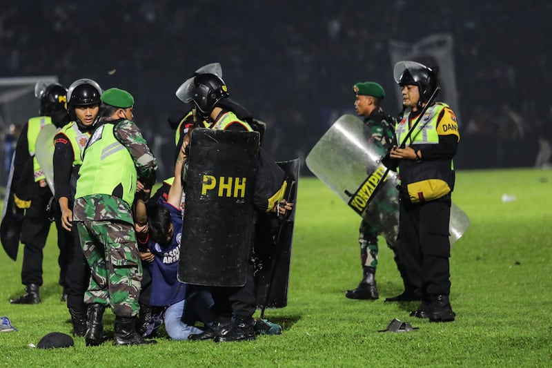 Police officers arrest a fan on the pitch during a clash between fans at Kanjuruhan Stadium. EPA